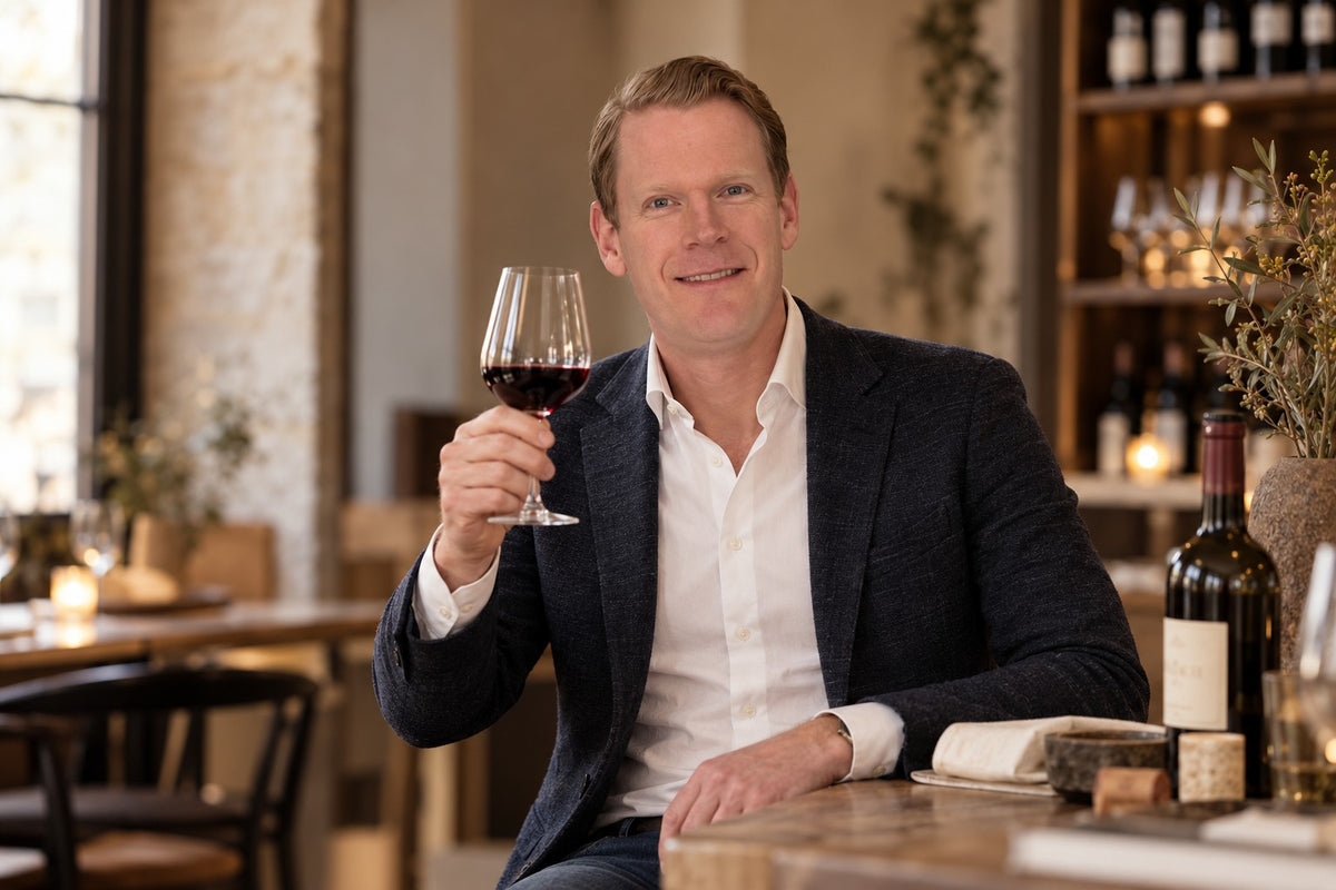 Maarten, mede-oprichter en curator van Élan, met een glas rode wijn aan tafel